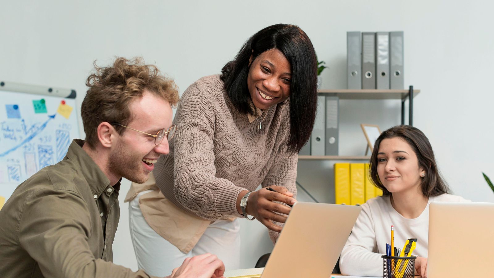 Um homem e duas mulheres em frente ao computador no trabalho