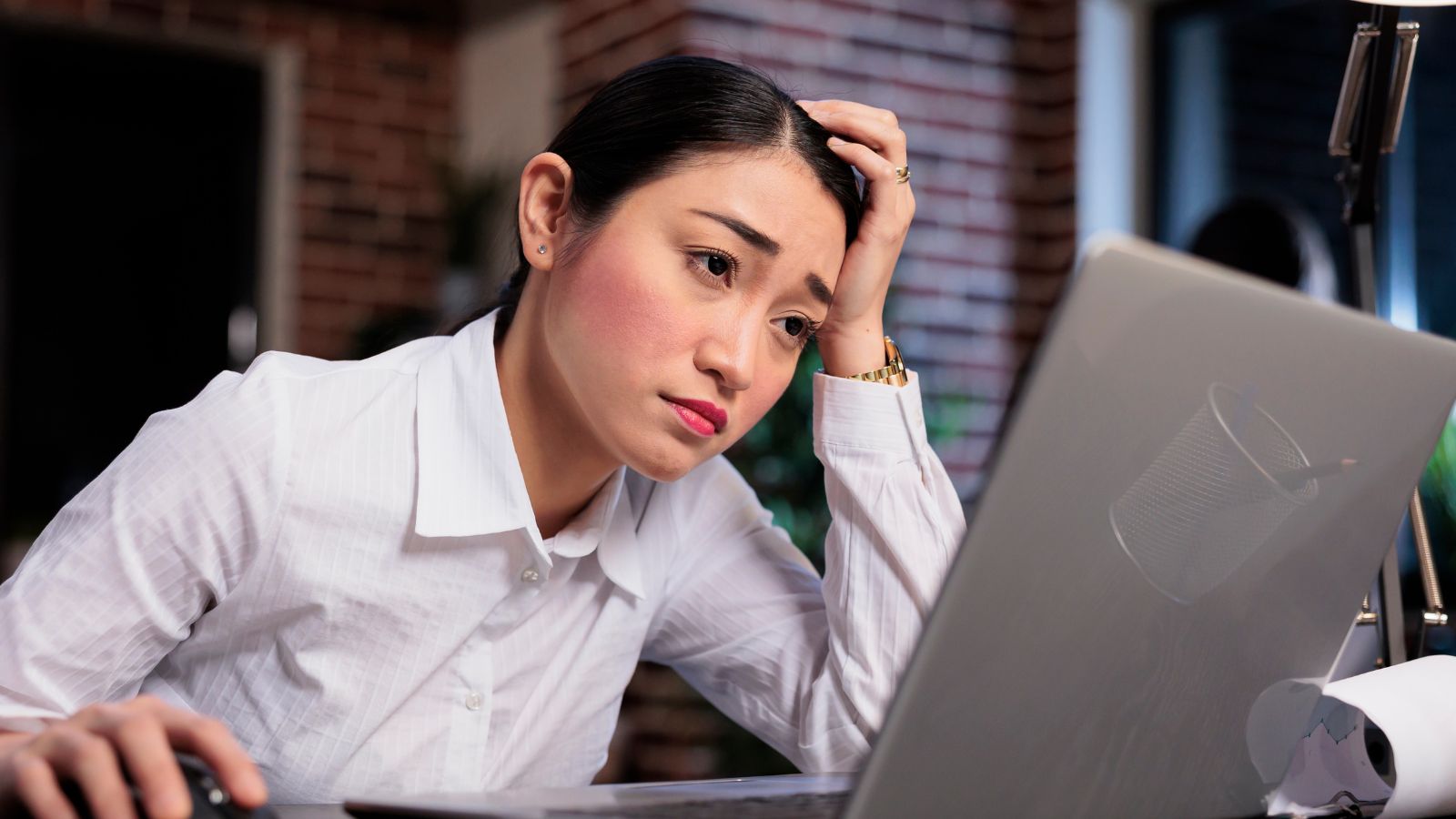 Mulher em frente ao computador com olhar triste