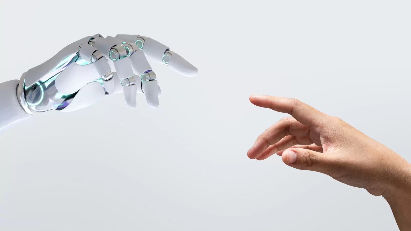 Mão robótica e mão humana quase em contato uma com a outra.