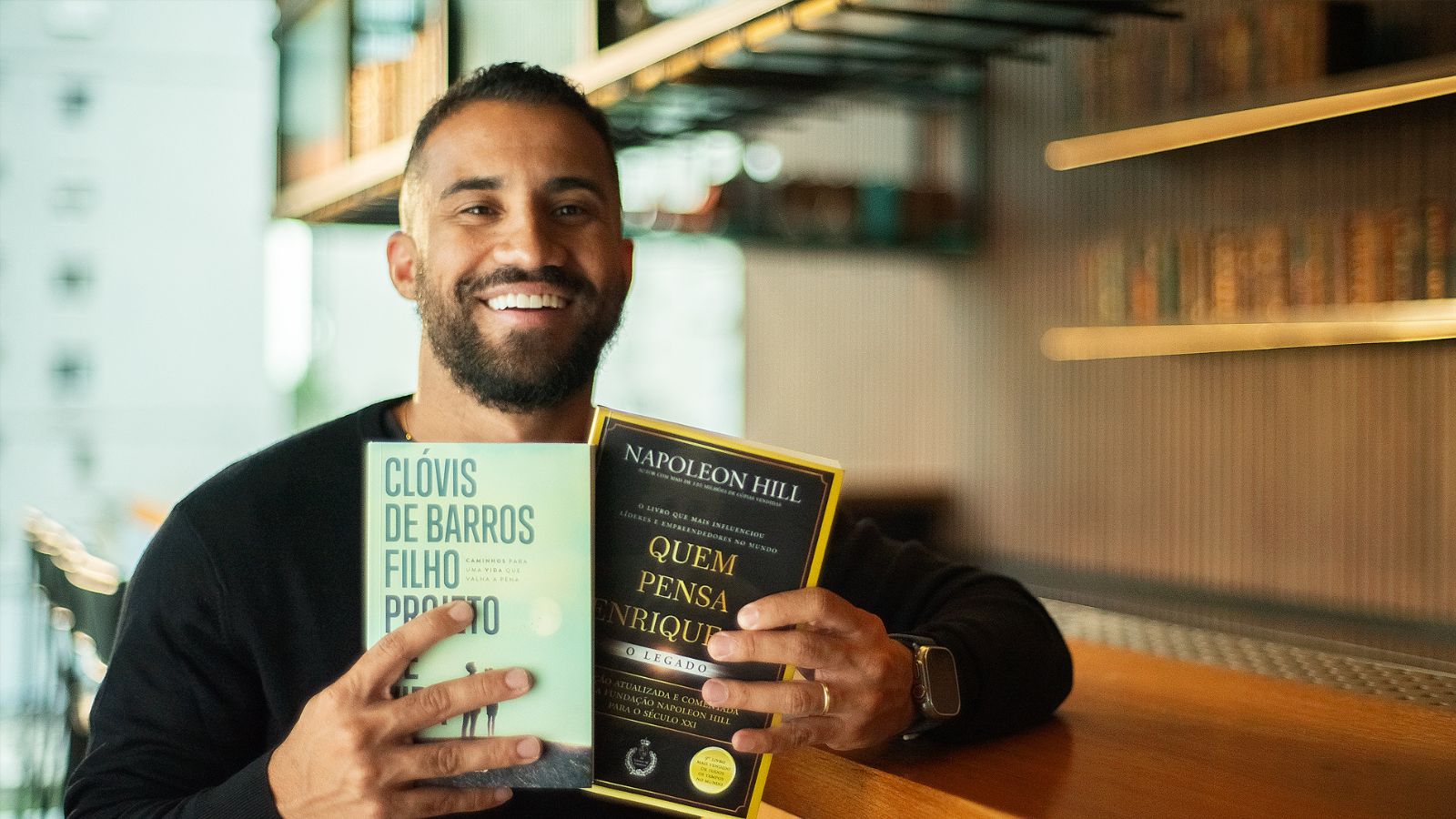 Fundador do Instituto Kondzilla segurando os livros “Quem Pensa Enriquece”, de Napoleon Hill, e “Projeto de Vida”, do filósofo Clóvis de Barros Filho