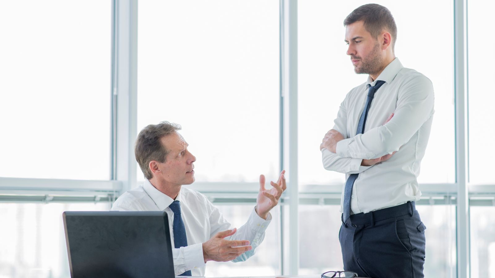 chefe sentado brigando com o funcionário em pé