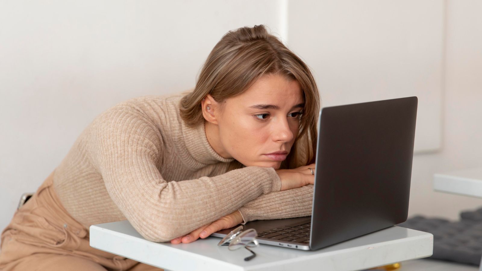 Jovem com semblante triste olhando para o notebook