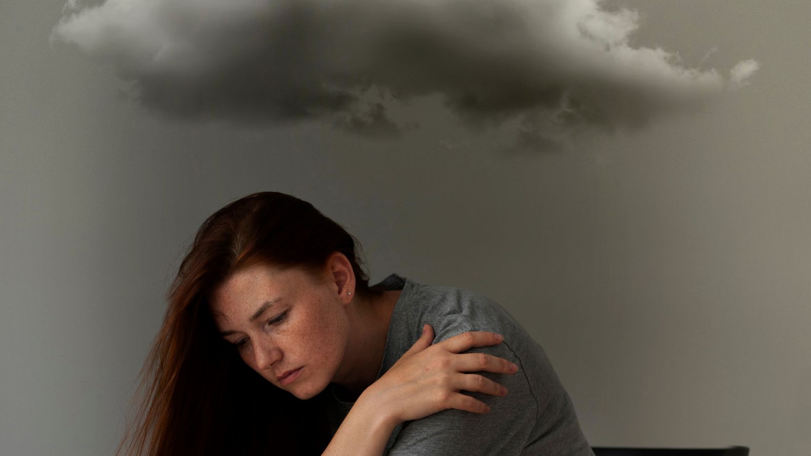Mulher triste sentada na cadeira com nuvem encima dela
