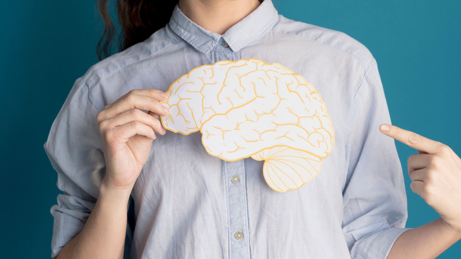 Mulher segurando desenho de cérebro em frente ao corpo