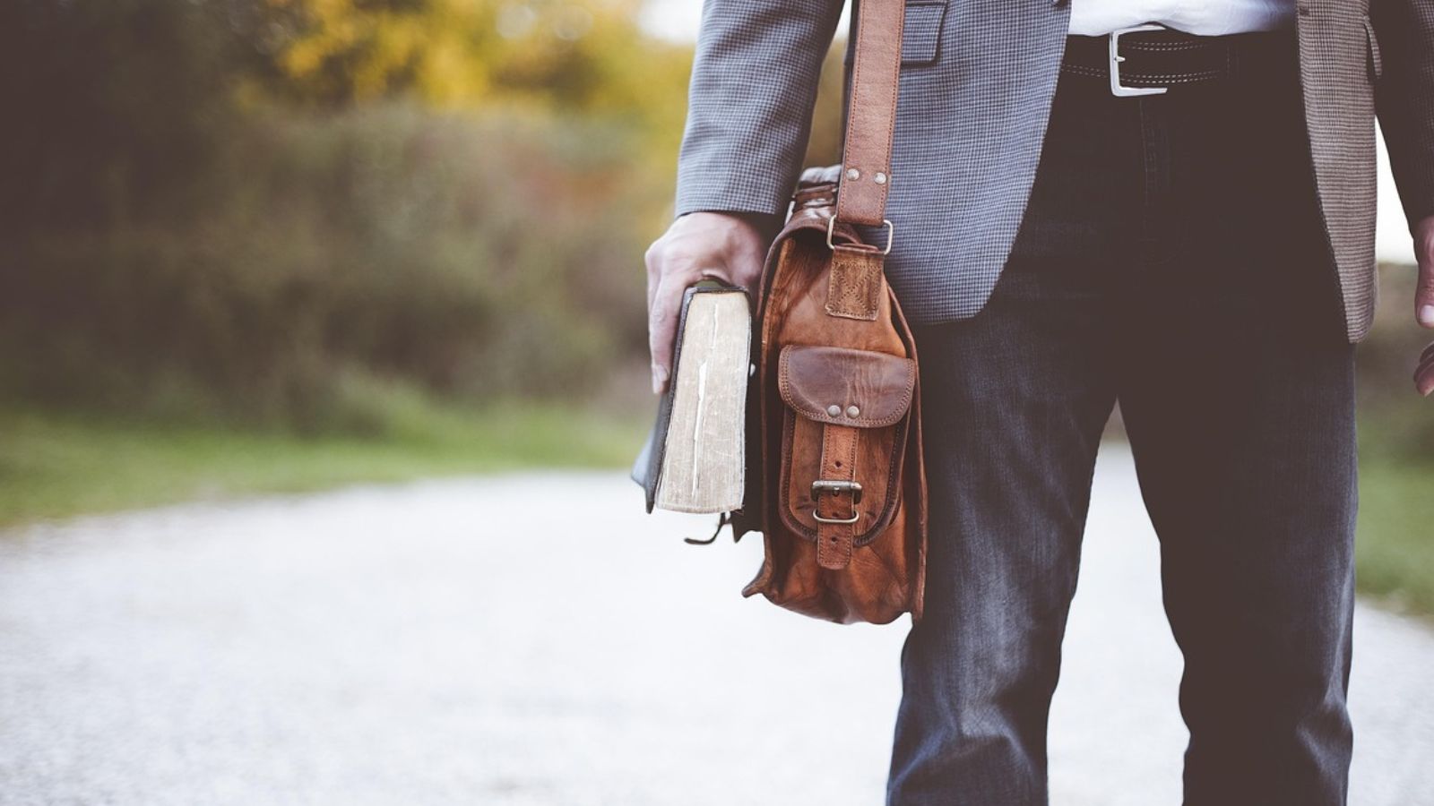 Homem com bolsa segurando livro