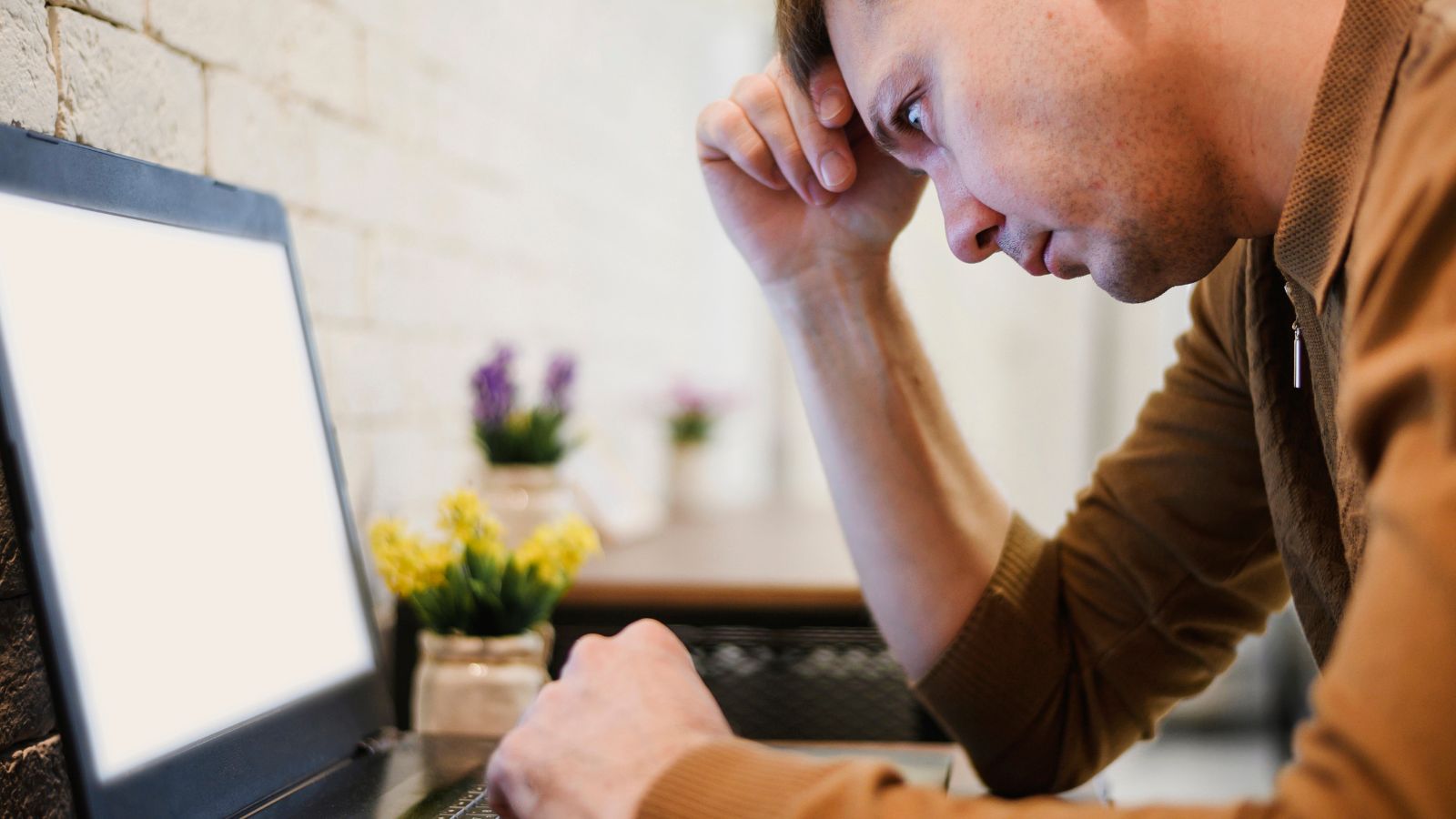 Pessoa mexendo em computador com semblante triste