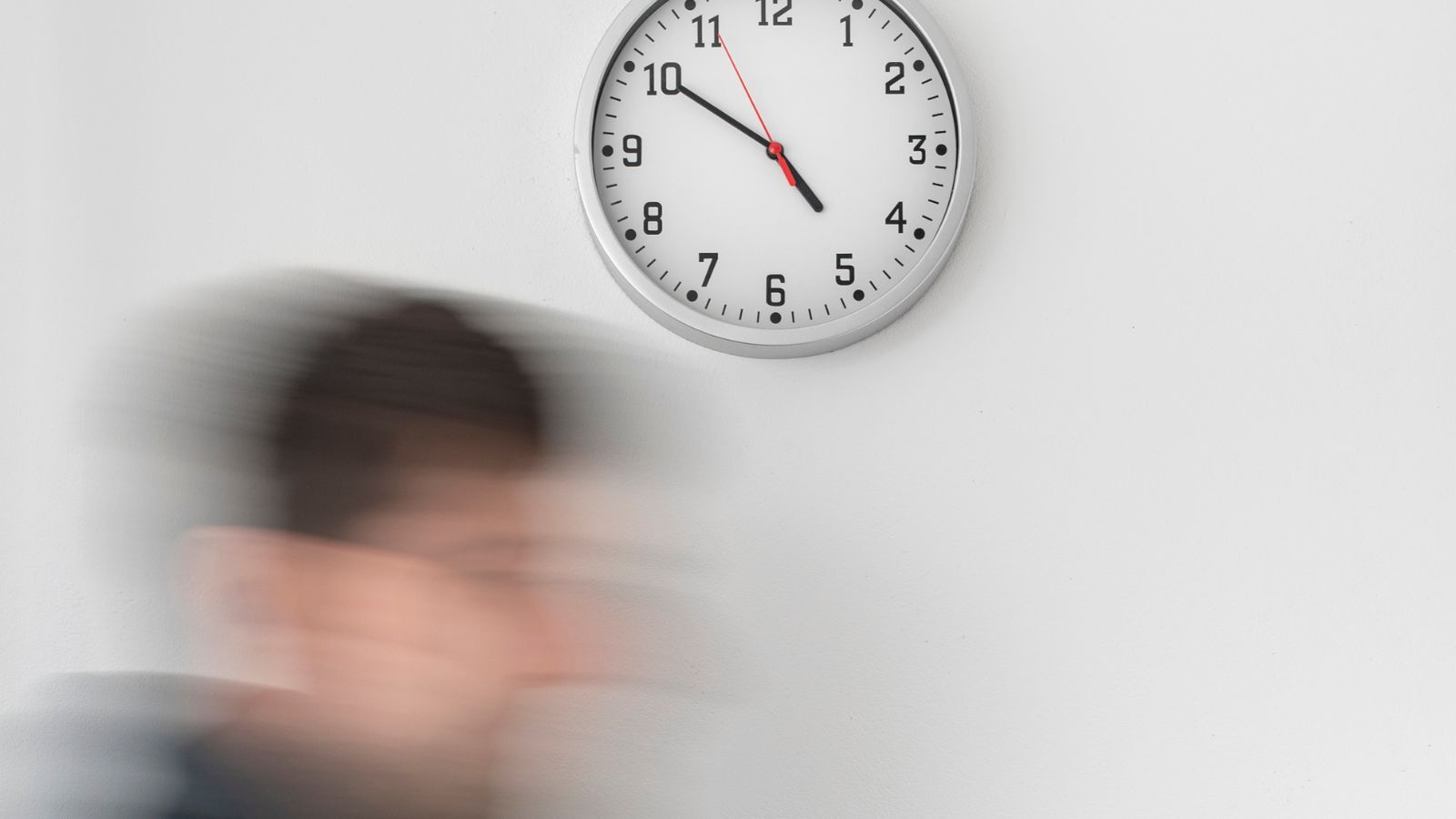 Homem correndo e relógio ao fundo